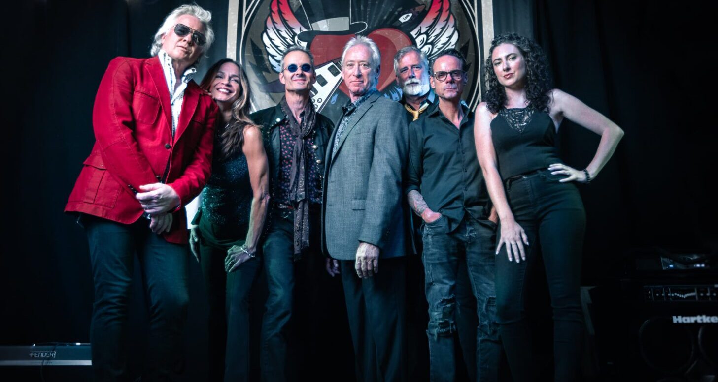 Band posing in front of Petty-themed backdrop.